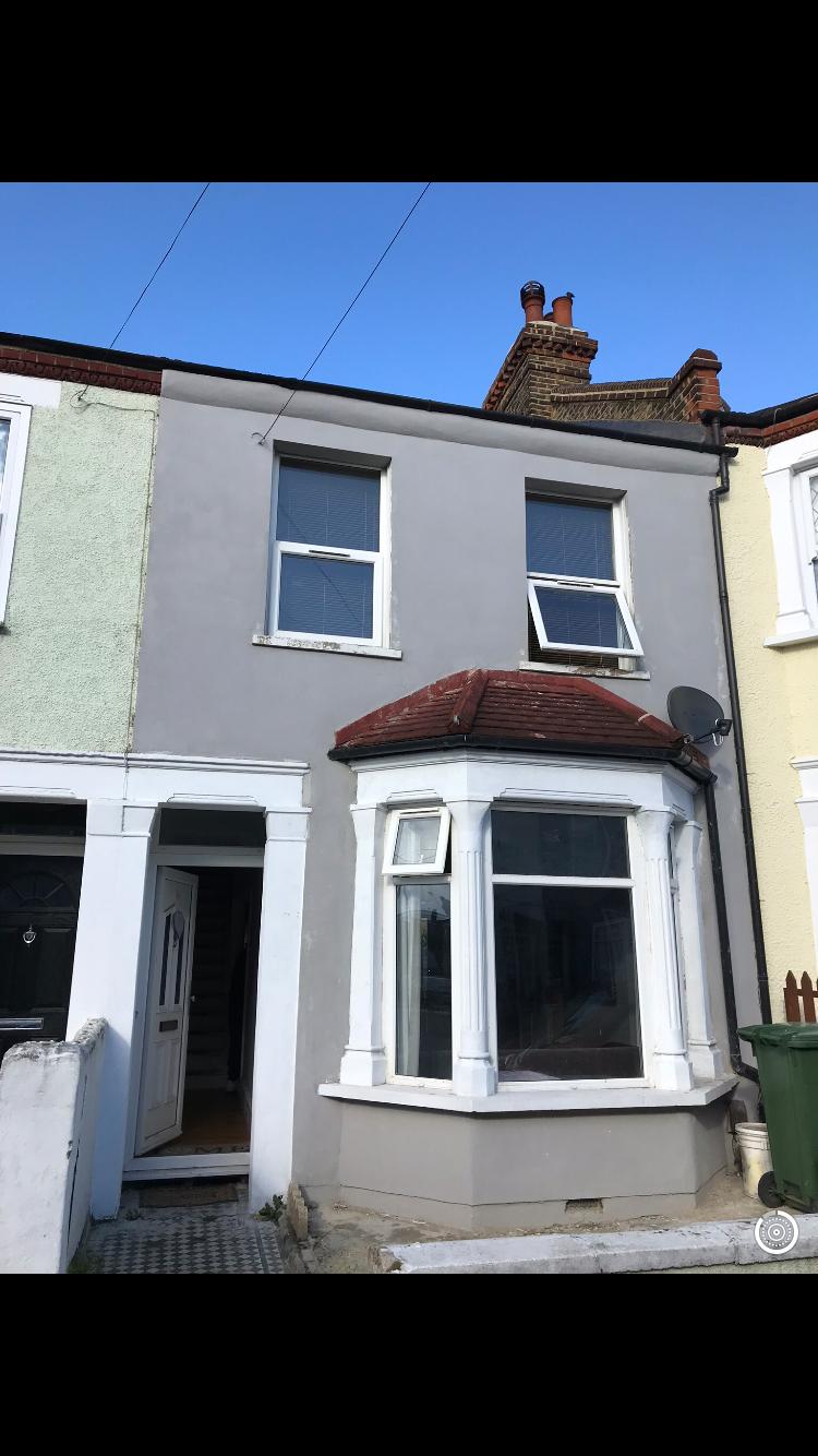 Terraced house front elevation covered in flat grey painted render before works