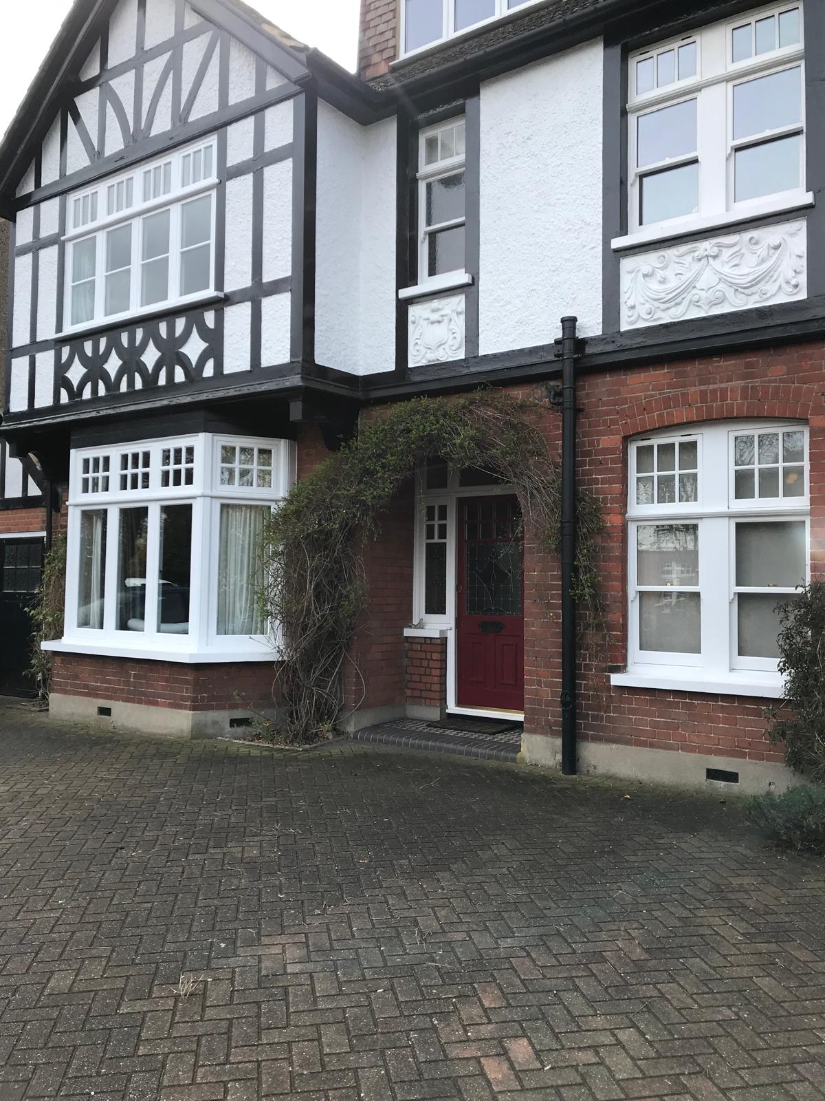 Repaired and recoated white render panels on a period mock-Tudor house frontage